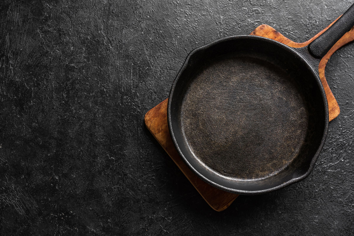 空铸铁煎锅烹饪黑色背景，俯视图，复制空间。烹饪概念背景与黑色平底锅