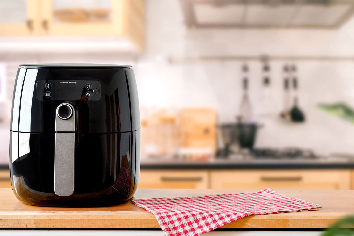 一个电动空气炸锅在桌子上模糊的厨房背景。bd手机下载烹饪新常态的生活方式。