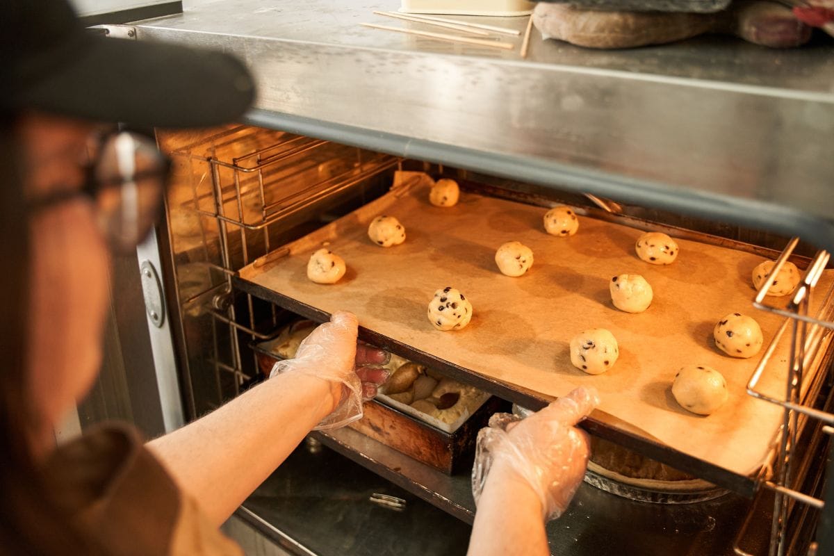 面包师在做饼干的时候，把装有面团的托盘放到烤箱里