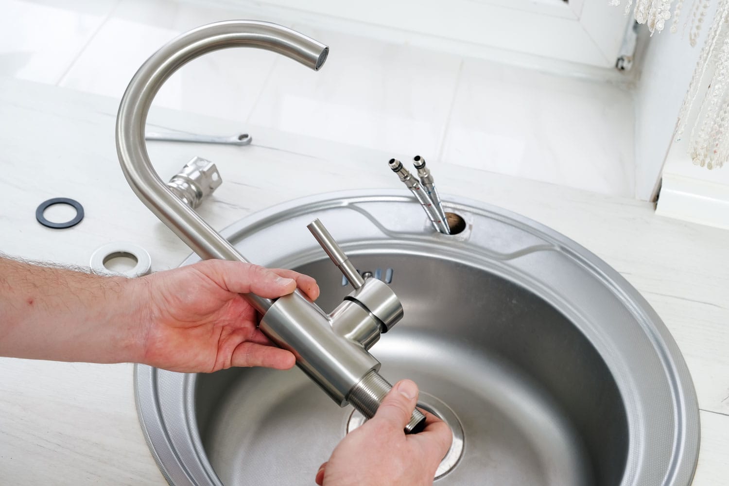近距离水管工手拿一个新水龙头安装到厨房水槽，管道工程或装修bd手机下载＂width=