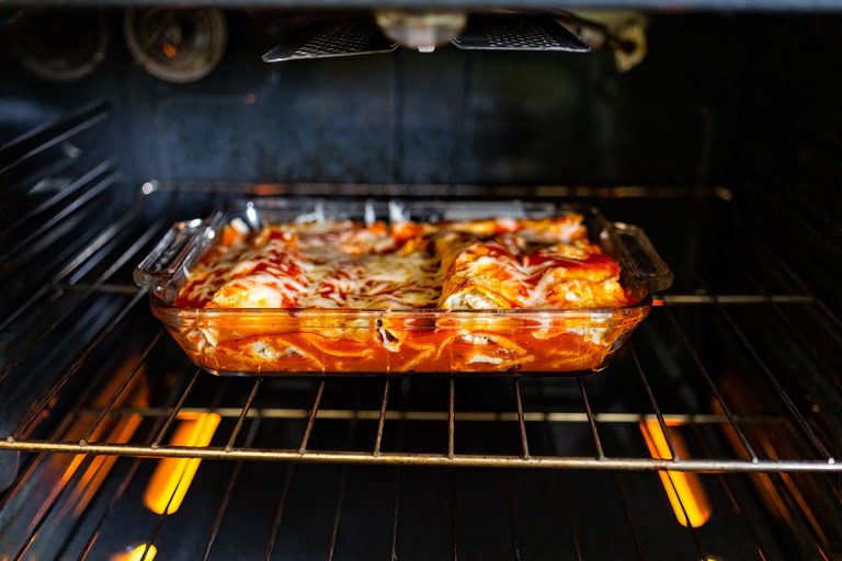 在炉架和自制的墨西哥食物卷在玻璃烤盘菜肴烹饪西红柿酱,玉米和奶酪,你应该烤馅饼覆盖或发现了吗?
