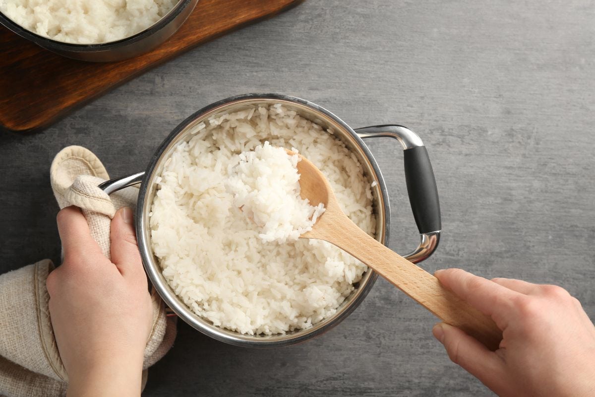 女人用勺子在平底锅里搅拌米饭。——米饭放冰箱前应该放凉吗?