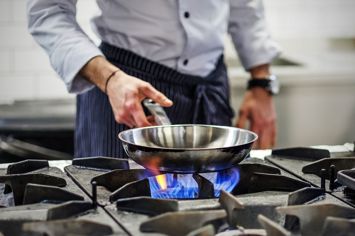 煤气炉上的煎锅。厨师控制烹饪过程