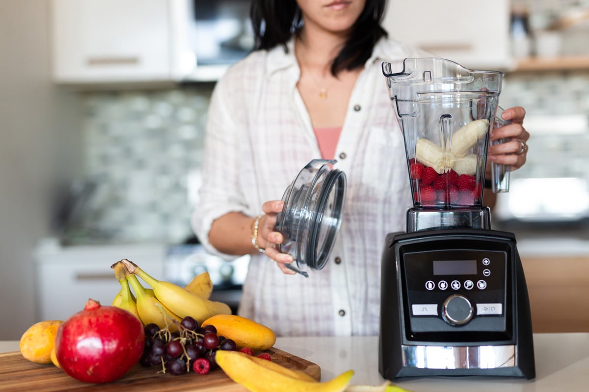 女人做美味的水果奶昔使用Vitamix搅拌机,Vitamix重置按钮在哪里?快速故障排除指南