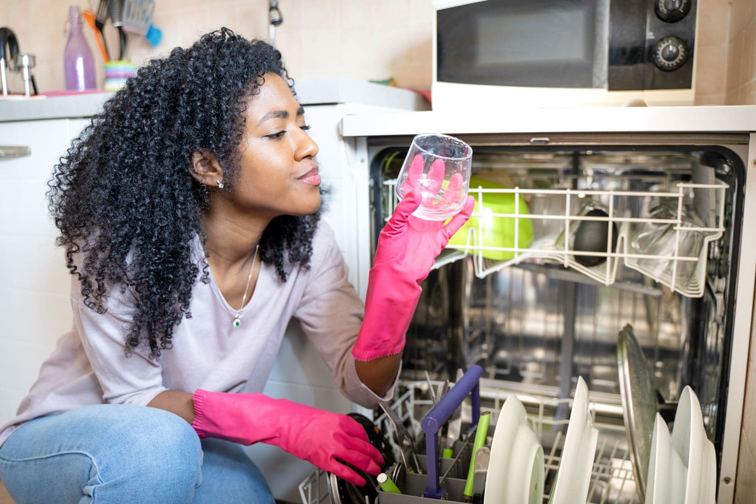 一个黑人妇女在家检查破碎的洗碗机