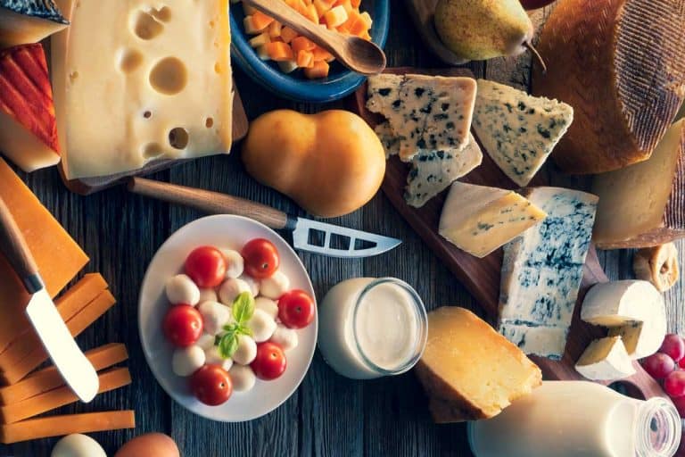 奶酪板与许多不同的奶酪和奶制品在桌子上芝士刀,为什么会有一个洞在一个芝士刀吗?