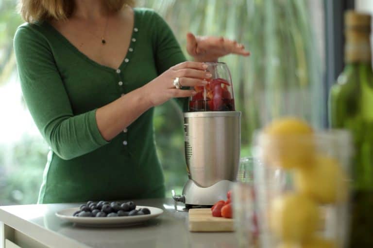 女人在她搅拌机混合很多品种的水果,你可以使用一个Nutribullet搅拌机?