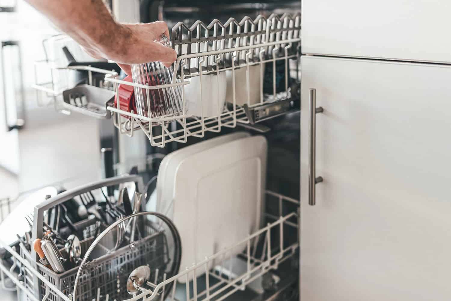 男人在厨房里装洗碗机或清空洗碗机的特写，如何让洗碗机过冬?bd手机下载