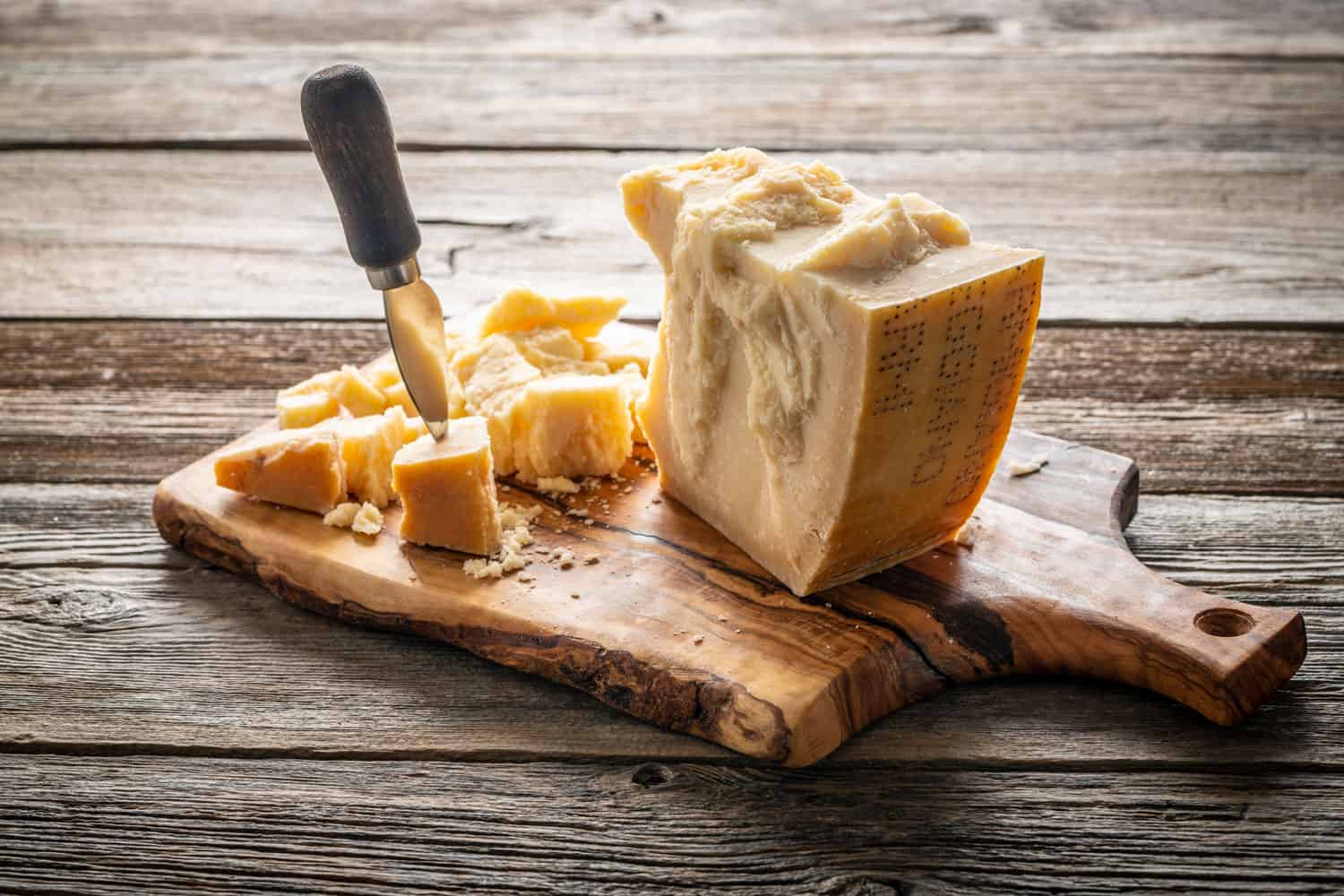 古老的切达奶酪，形状不规则，大小不一，放在木制的奶酪板上