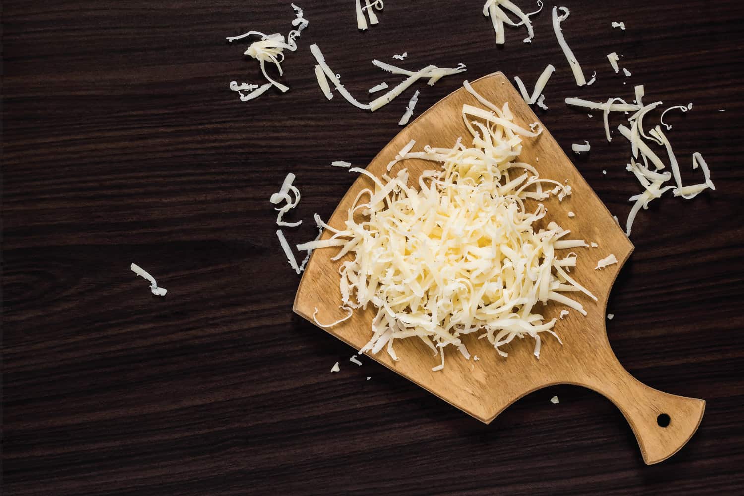 在深色背景的切菜板上烹饪用的磨碎的奶酪