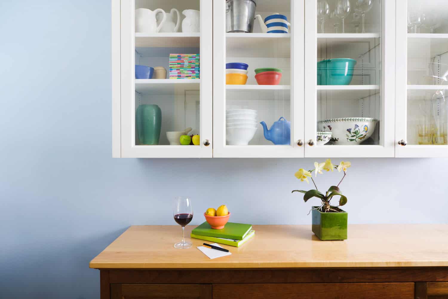 一个组织良好的厨柜，柜台和橱柜，展bd手机下载示了一杯酒，书籍，鲜花和家庭用品在一个干净，整洁，新粉刷的家庭内部。