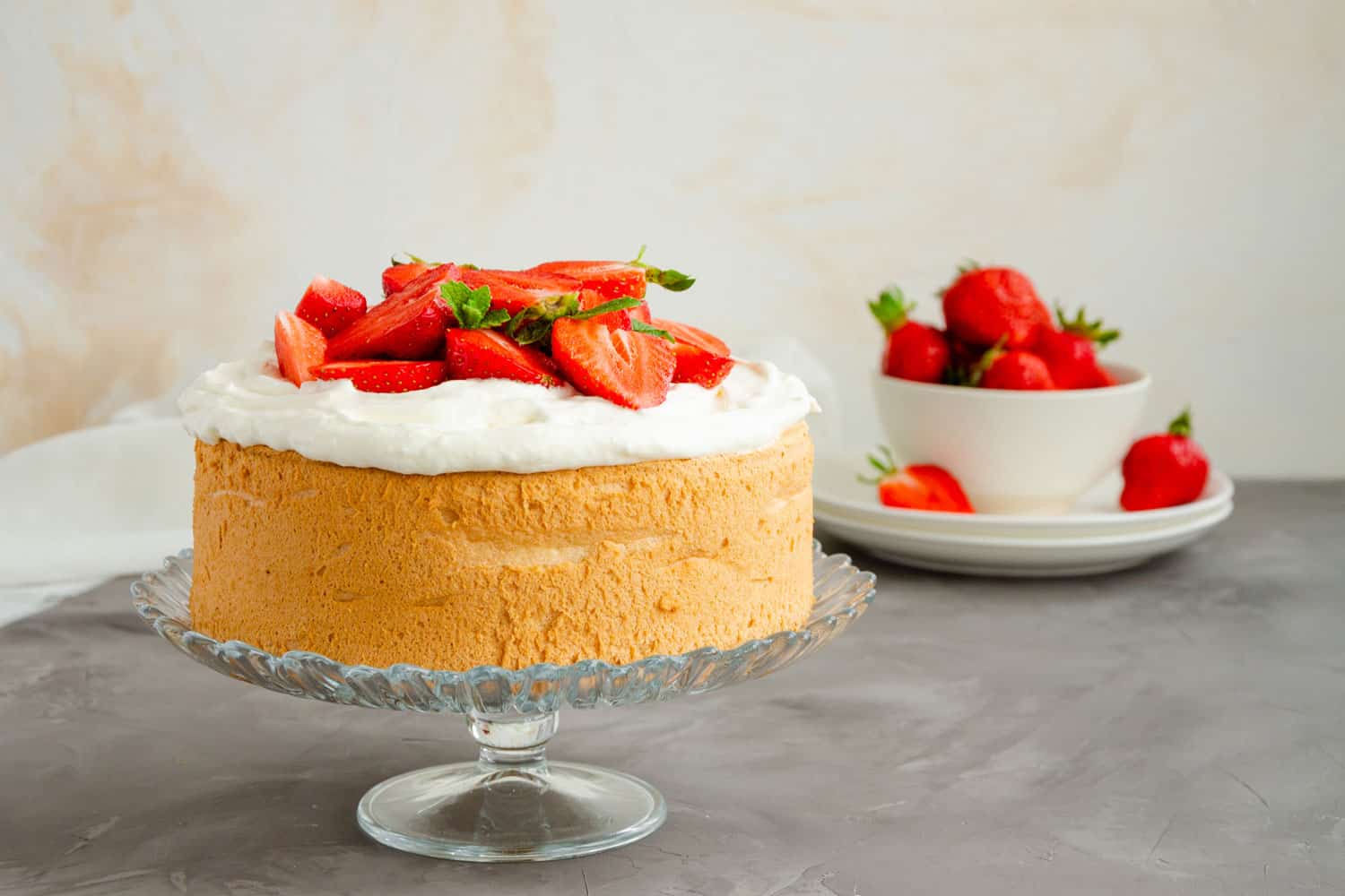 天使蛋糕，上面有鲜奶油和新鲜草莓片，背景是混凝土