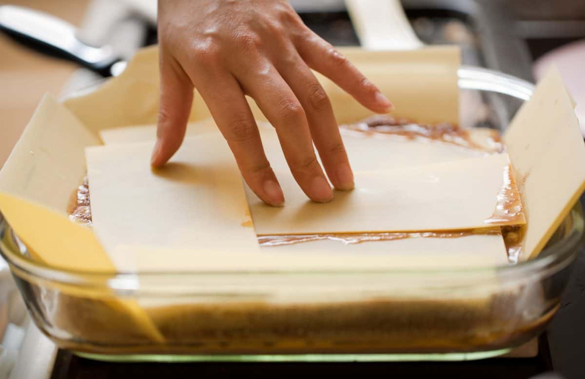女性的手整理千层面意大利面，为烤箱做准备。