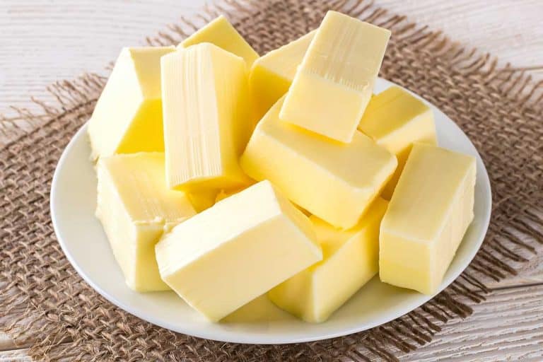 矩形块新鲜的黄色奶油白色飞碟在白色木制桌子,你可以加盐无盐黄油吗?