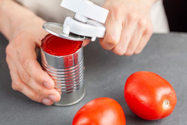 一个女人小心翼翼地打开一罐西红柿酱厨房柜台上使用白色塑料开罐器,如何使用一个养尊处优的厨师开罐器bd手机下载