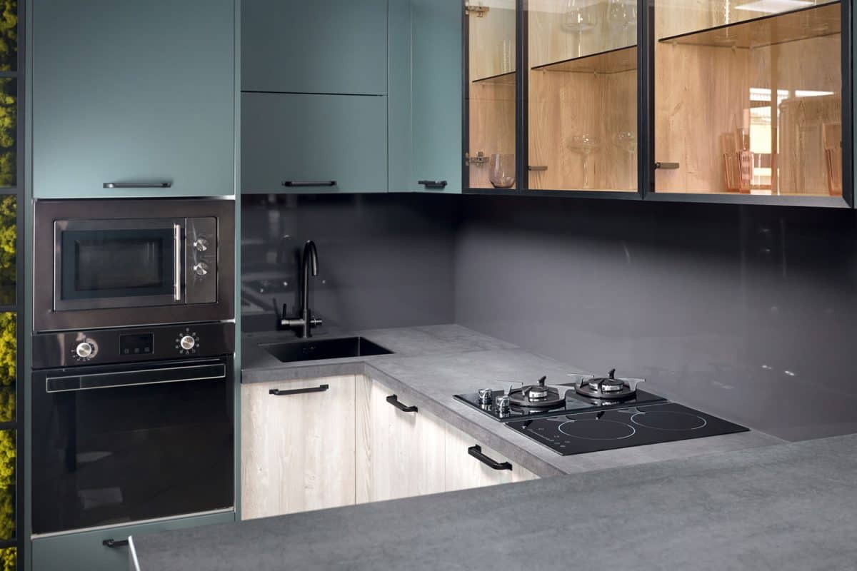 一个超现代的厨房，有浅蓝色漆的橱bd手机下载柜，玻璃镶板橱柜和灰色的台面