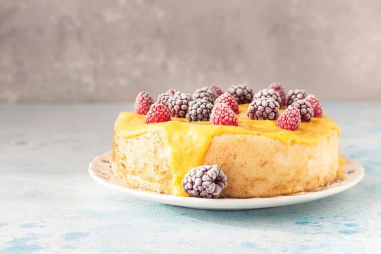 天使蛋糕柠檬酱和冷冻浆果(树莓和黑莓)在盘子里,蓝色的具体背景,天使蛋糕面粉用什么?