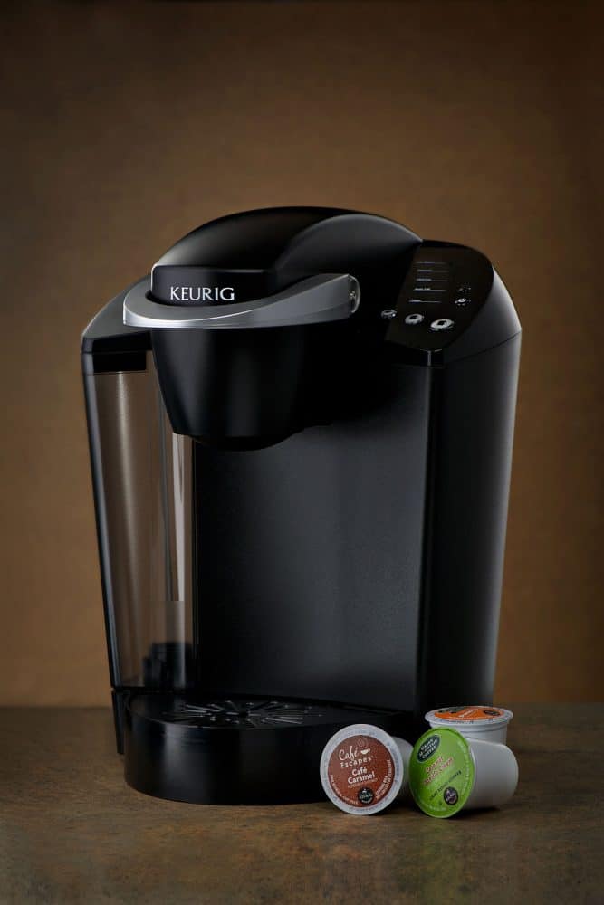 Keurig咖啡机，旁边有三个杯荚