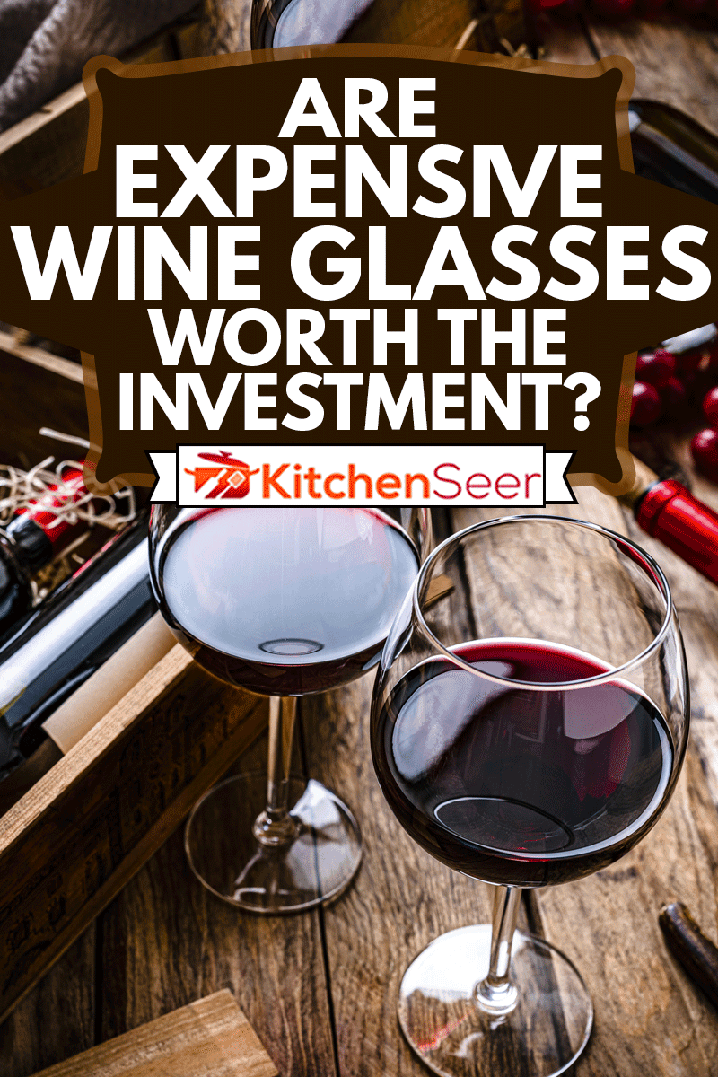 在乡村木桌上拍摄的两个红色酒杯，高角度视角，昂贵的酒杯值得投资吗?