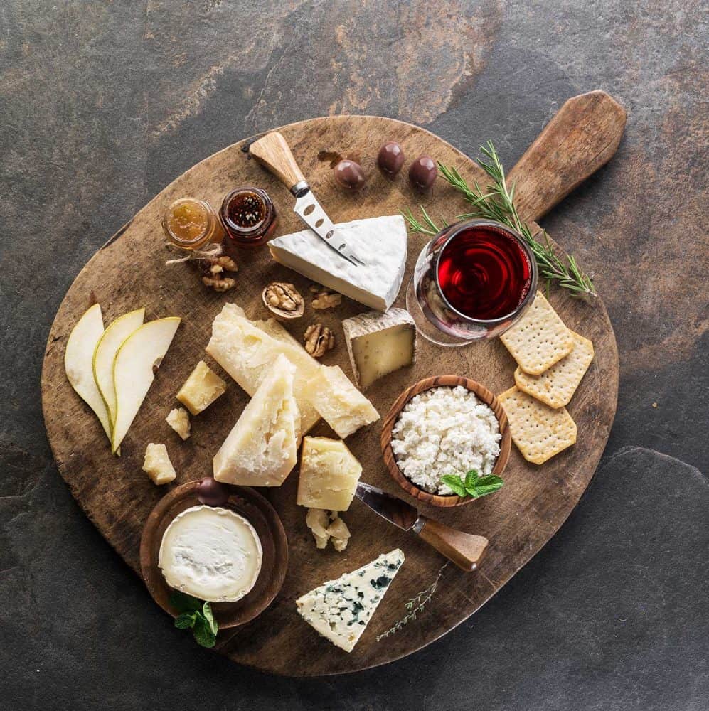 奶酪拼盘与不同的奶酪，水果，坚果和葡萄酒的石头背景＂width=