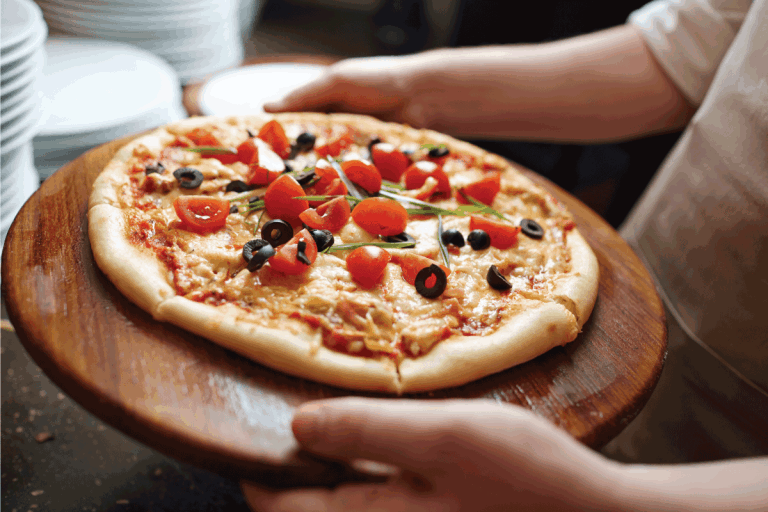 Chef-carrying-tasty-pizza, -Pizza-Tray-VS-Stone-What-Are-The-Differences
