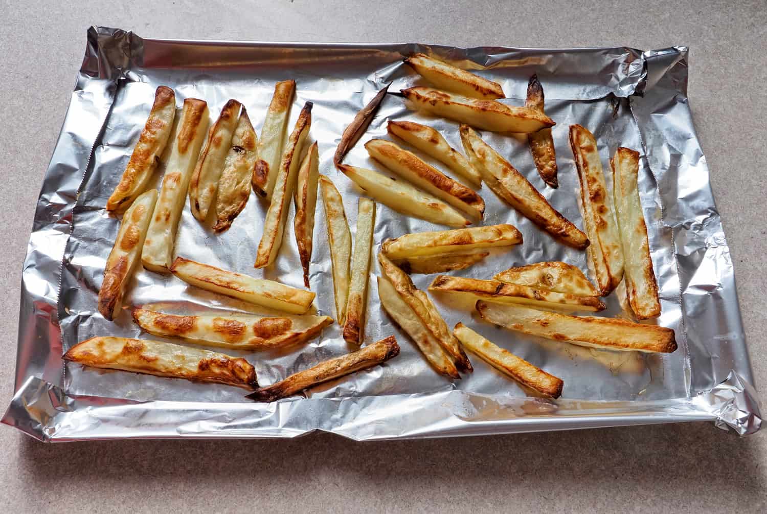 家里准备好烤好的薯条，用新鲜的土豆片和橄榄油煮熟，放在铝箔纸上。