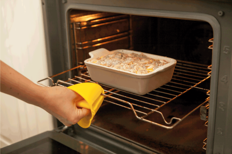 硅胶手套的厨房,女人把腿从烤箱使用硅胶bd手机下载手套。是硅胶烤箱手套更好