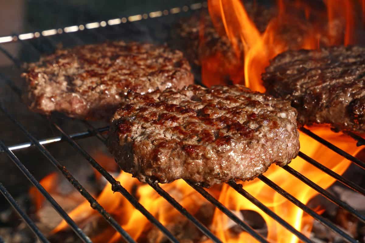 近距离拍摄牛肉或猪肉烧烤汉堡，供汉堡准备在烧烤火上火焰烧烤，高角度观看