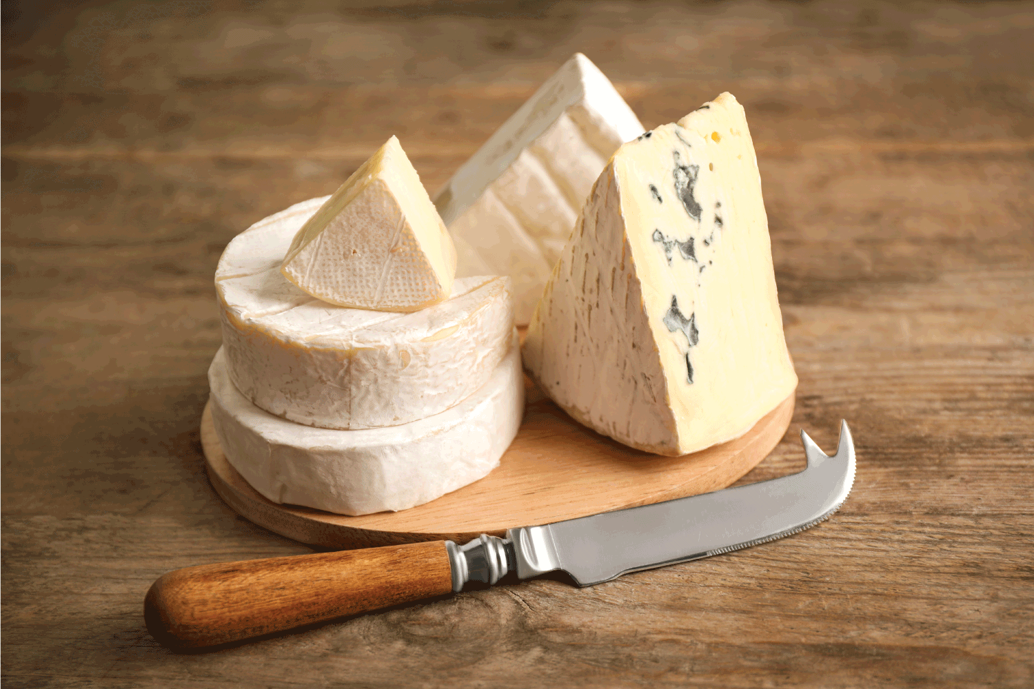 不同类型的奶酪和刀在木桌上与尖头的奶酪刀