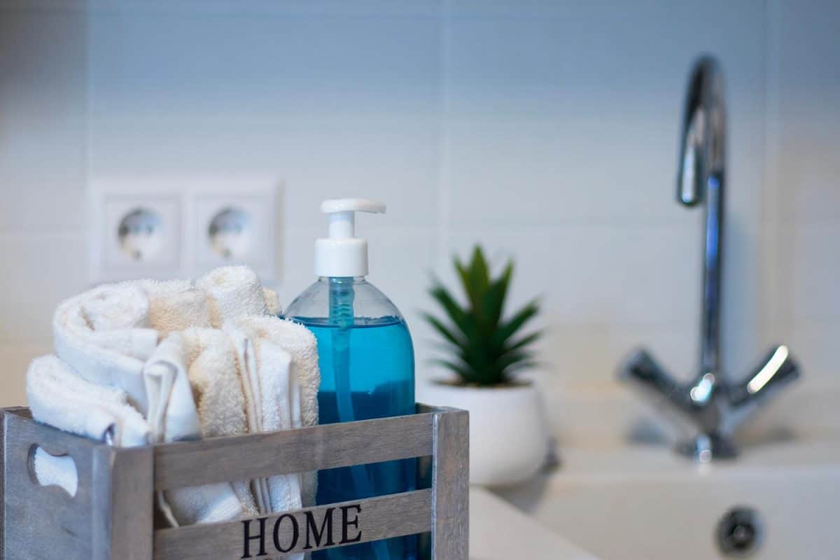 液体蓝色肥皂在透明塑料分配器旁边的手巾
