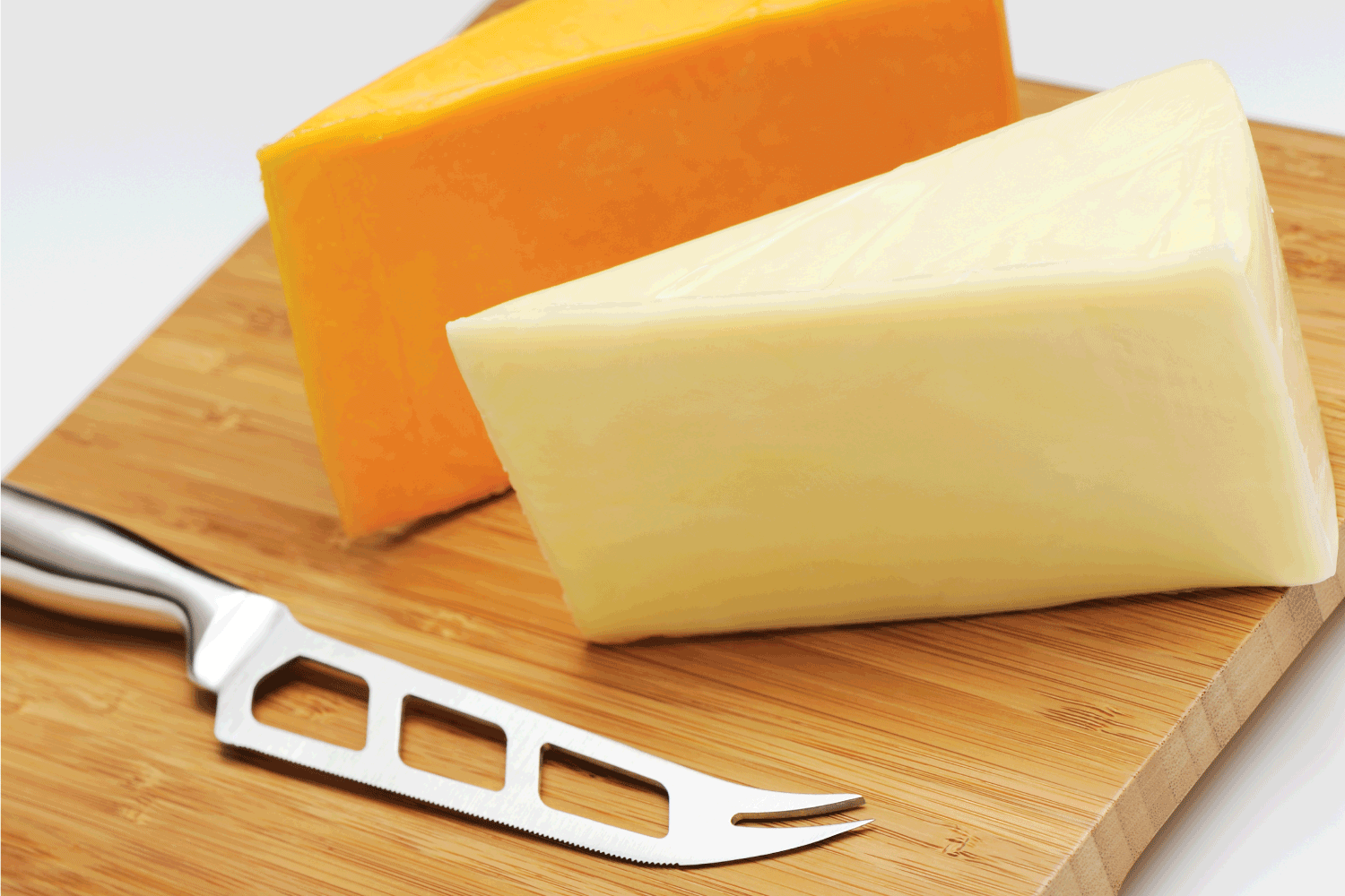 用奶酪刀在砧板上切两片切达干酪(白色和黄色)。