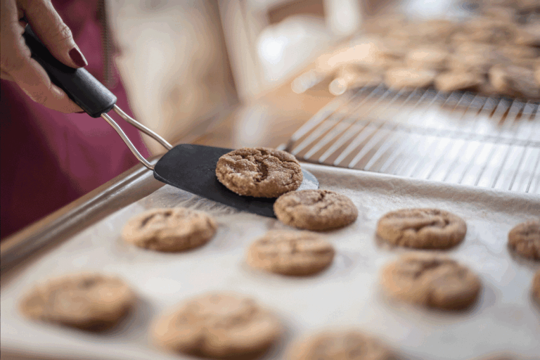 woman-using-a-spatula-to-fetch-cookies-from-a-baking-tray.-How-Long-To-Bake-Chocolate-Chip-Cookies