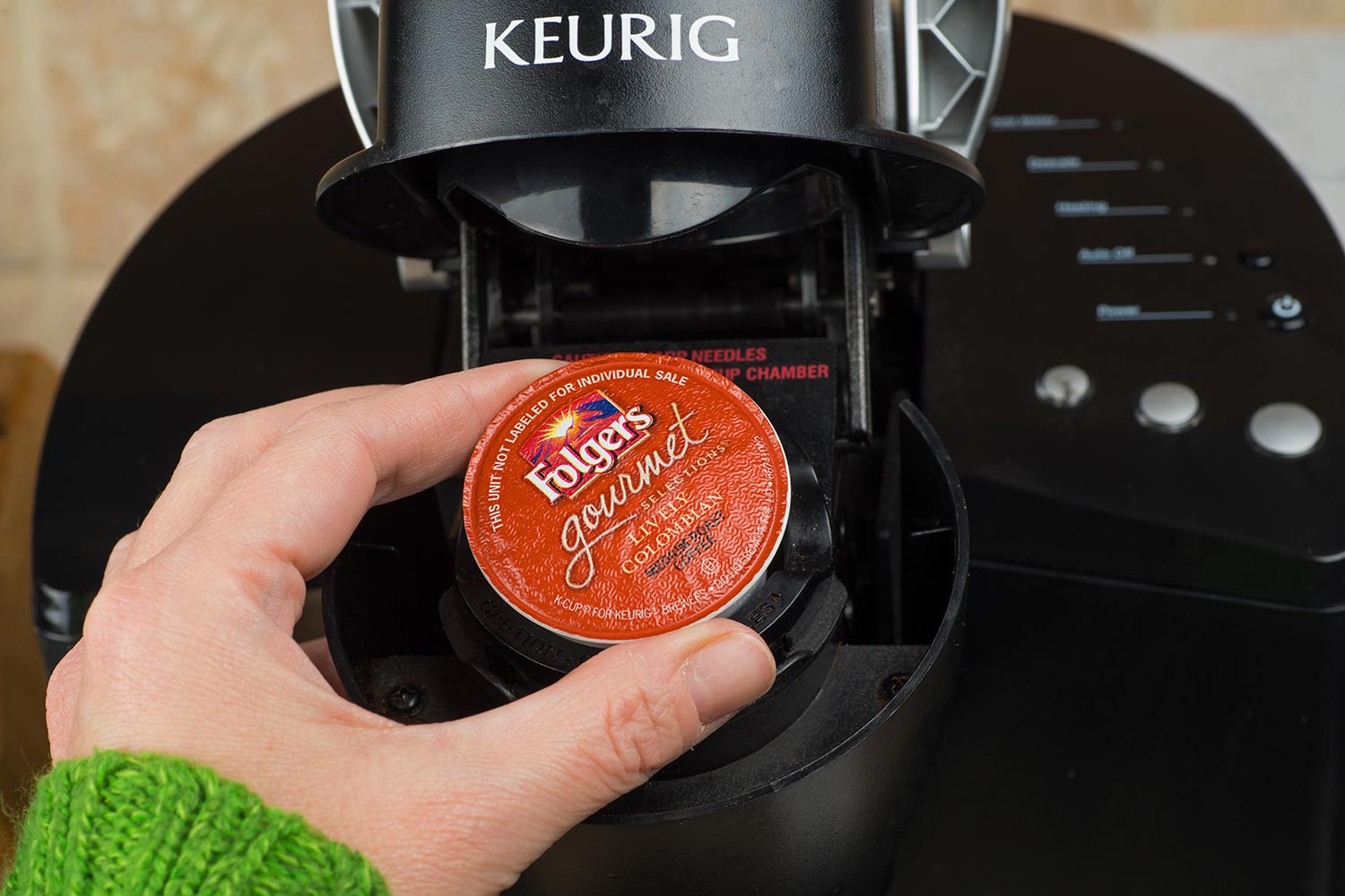 一名女子将单杯k杯Foldger咖啡插入Keurig咖啡机