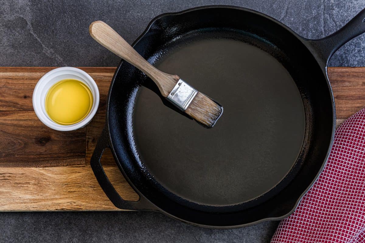 铸铁煎锅刷上橄榄油以防止粘锅，放在石板台面上，用红色抹布擦碗
