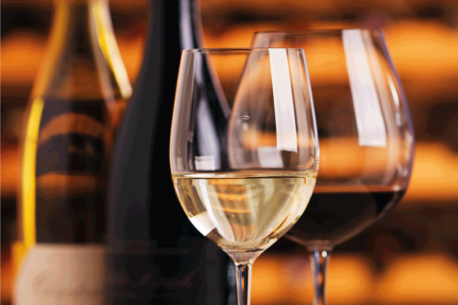 酒杯和酒瓶展示为品酒服务。红色和白色的发酵葡萄饮料被倒入两个闪亮的玻璃杯中。