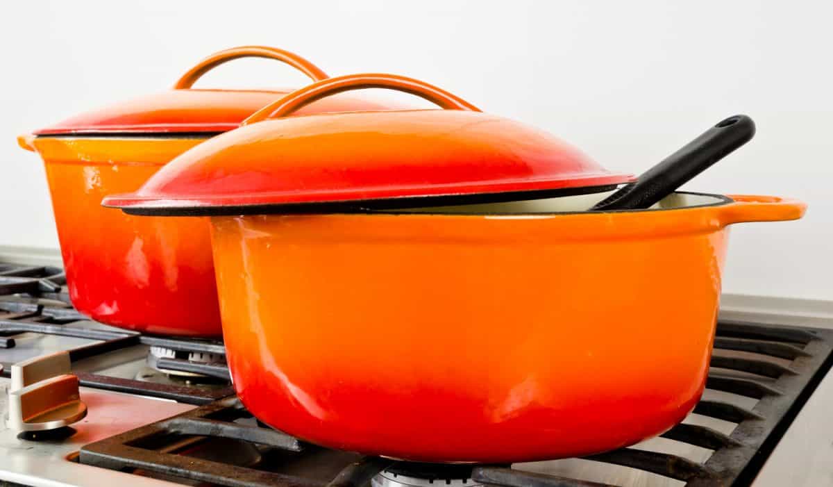 老式煤气炉旁有两个亮橙色的搪瓷铸铁锅