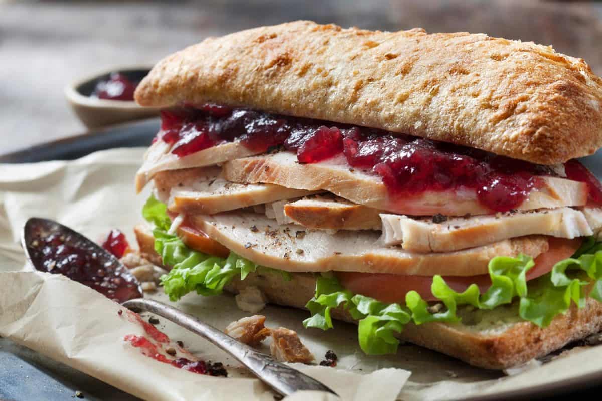 Roast turkey sandwich with lettuce, tomato and cranberry sauce on ciabatta bun