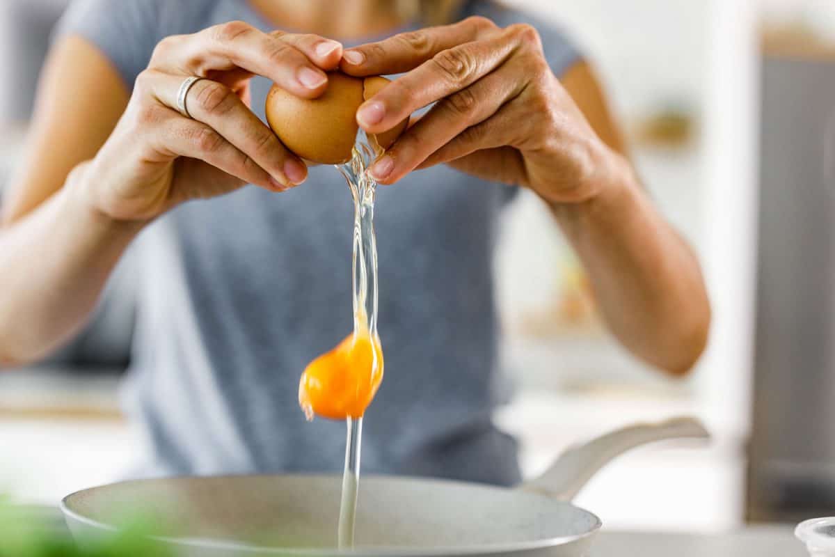 一个女人用手敲鸡蛋的焦点照片
