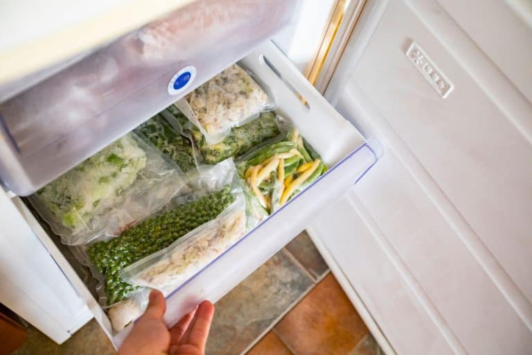 一个女人检查冰箱的抽屉里装满了蔬菜,怎样修理冰箱抽屉破碎