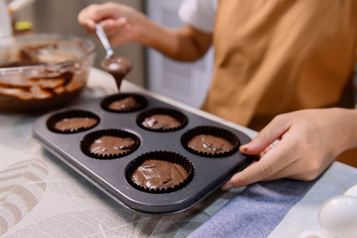 制作美味的自制松饼和万圣节小蛋糕的过程。女人在家里的厨房里准备和混合甜点的配料，松饼盘可以放在洗碗机里吗?bd手机下载
