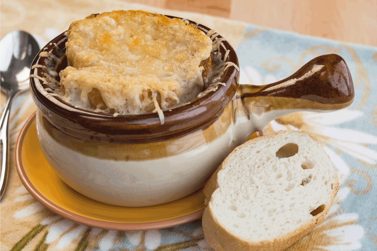传统缸顶部设有融化的格鲁耶尔充满法式洋葱汤,配上新鲜的法式面包。如何切洋葱法式洋葱汤