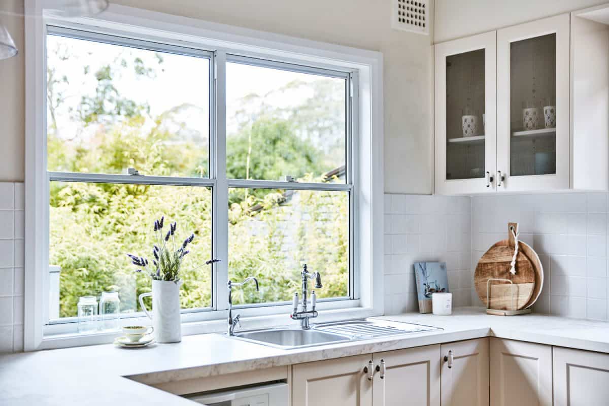 一个白色的现代厨房，有奶油色的bd手机下载橱柜和一个低矮的厨房窗户