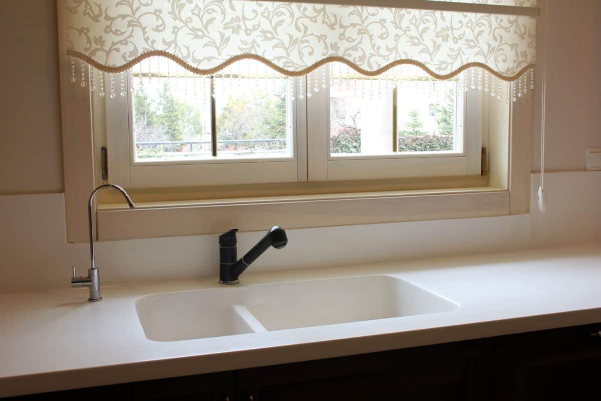 空厨房用白色台面花bd手机下载卉设计窗帘的窗口和一个小黑色的厨房水龙头