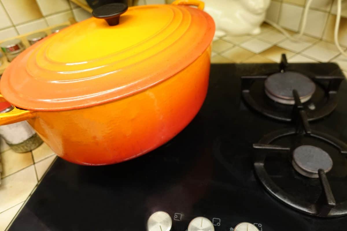 灶台上有个橙色的荷兰烤箱