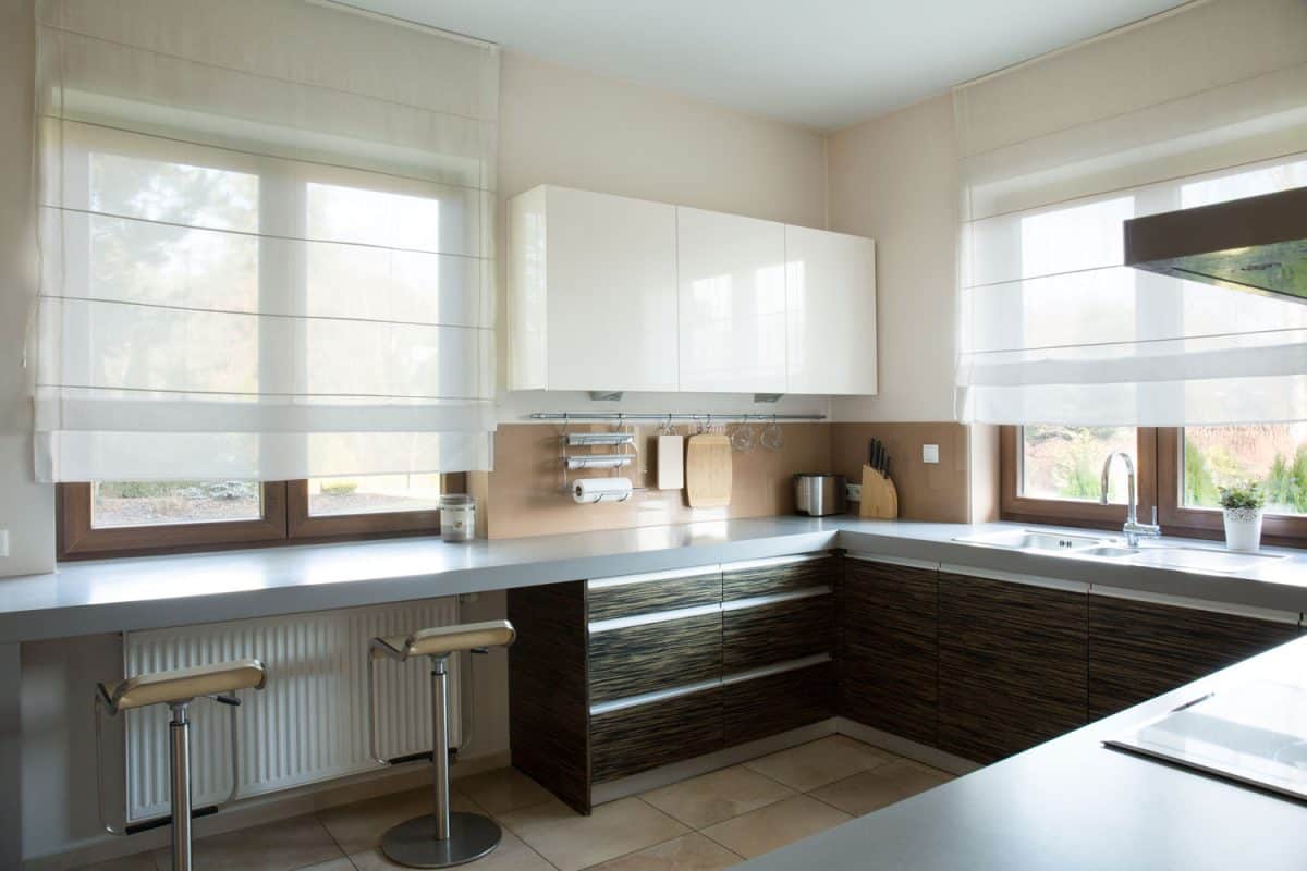大型和现代设计的厨房用黑色橱柜、浅灰色工作台面与窗帘bd手机下载和窗户