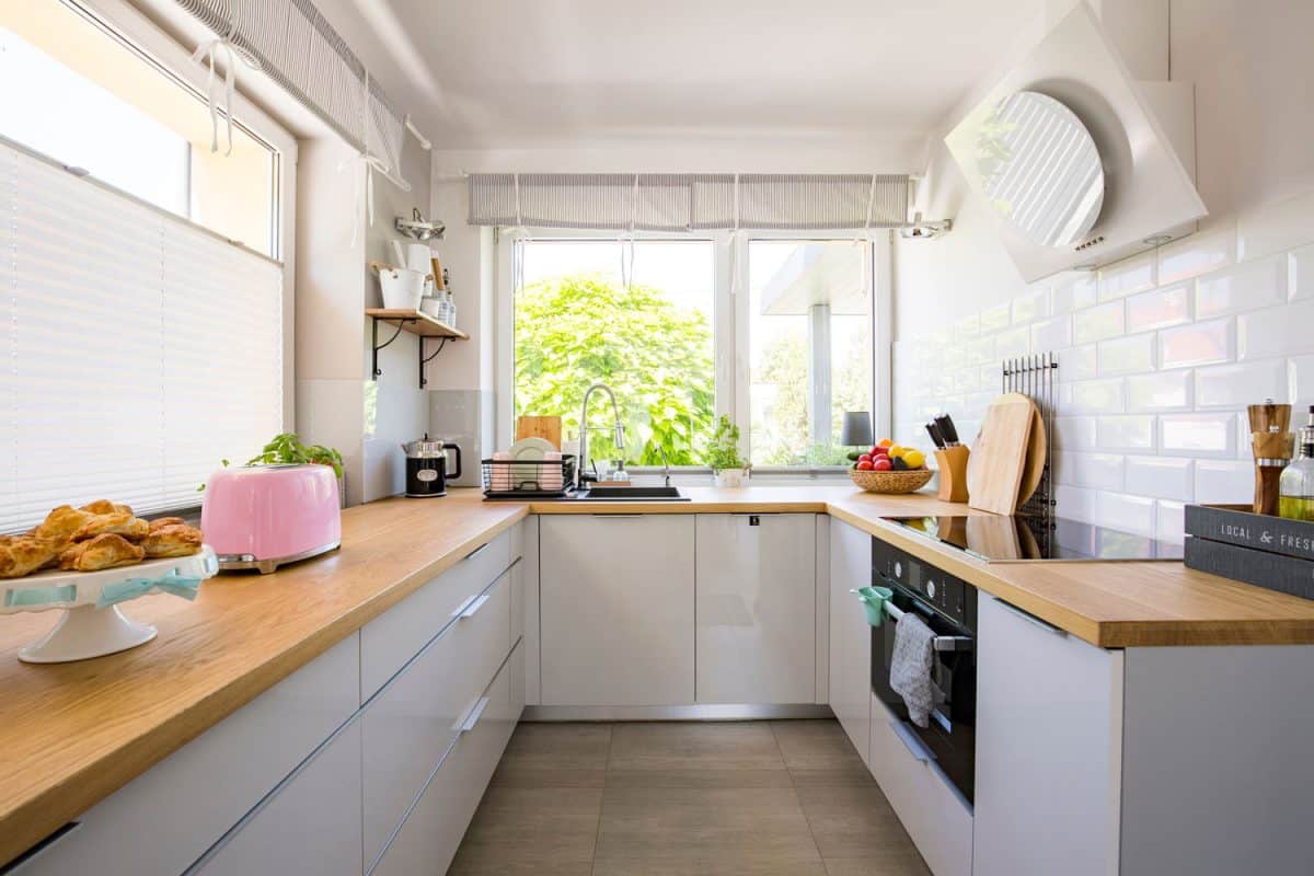 狭窄的厨房设计有木制台面，白色橱bd手机下载柜和一扇低窗