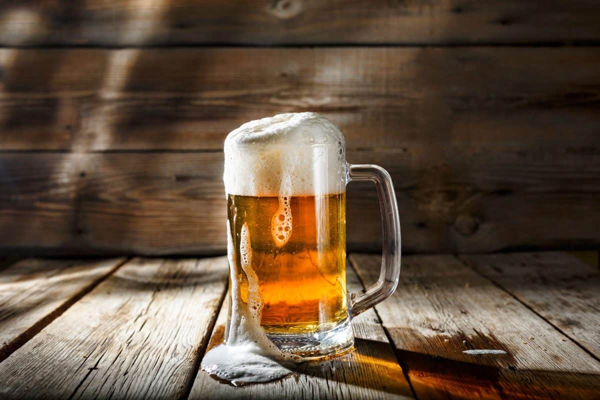 木桌上放着一只啤酒杯，里面盛着淡啤酒