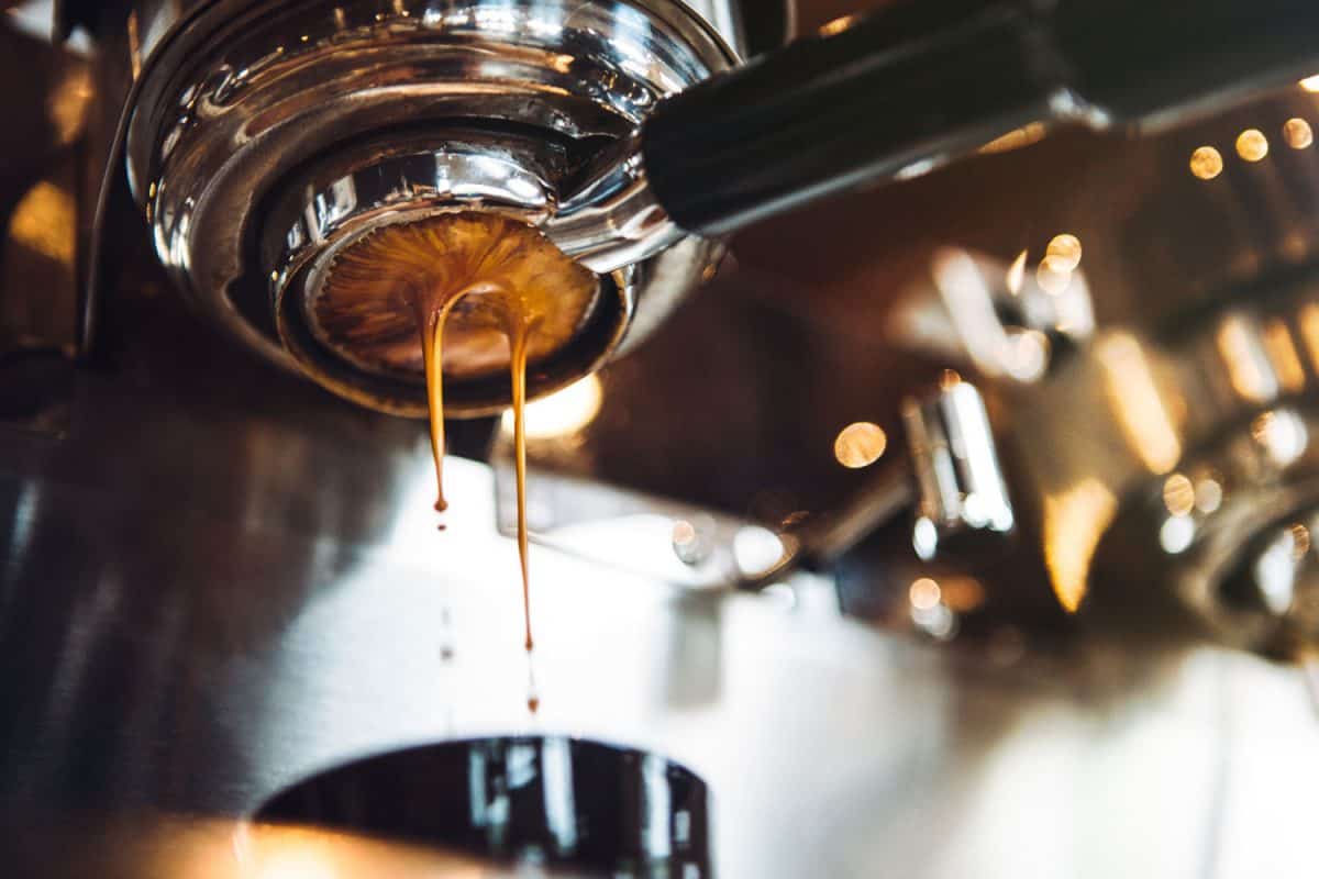 新鲜和热的浓缩咖啡从一个漂亮的铬浓缩咖啡机的过滤器倒。