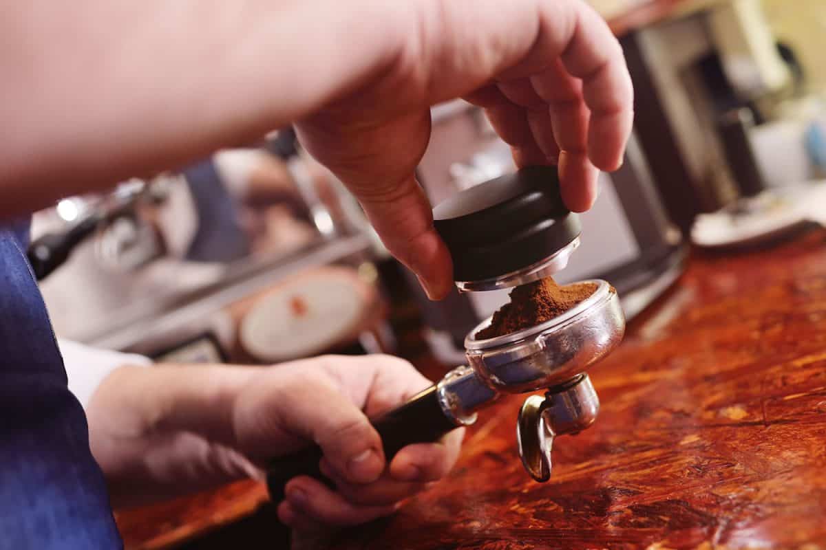 咖啡师用咖啡粉和捣固器在咖啡师手中形成咖啡丸