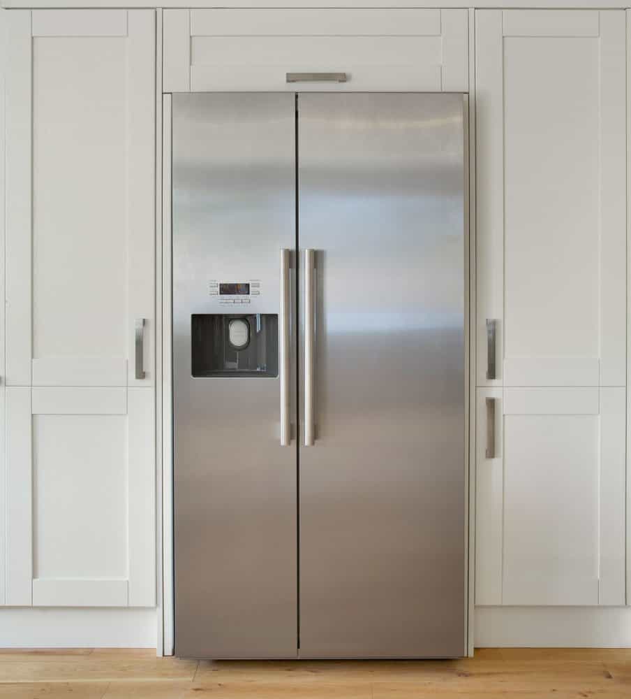 一种现代美式冰箱，放置在农舍式厨房里一排奶油色的橱柜里bd手机下载